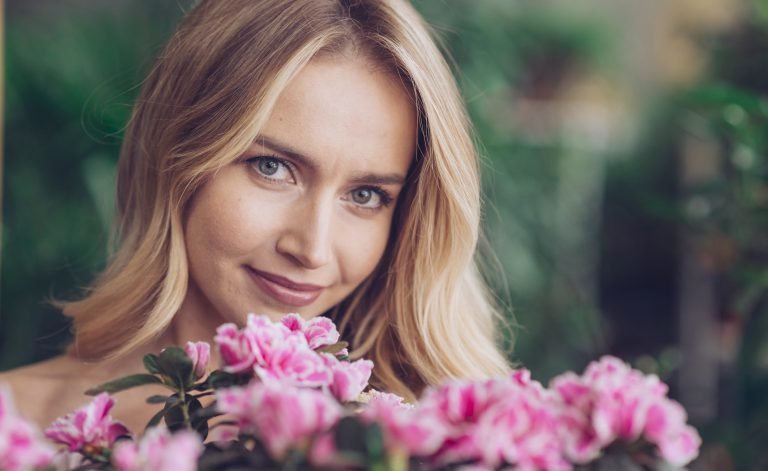 close-up-smiling-blonde-young-woman-with-pink-flowers-looking-camera